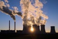 Steaming cooling towers of coal power plant against the sun Royalty Free Stock Photo