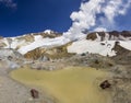 Steaming crater of active volcano covered by snow