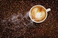 Steaming cup of coffee on coffee beans Royalty Free Stock Photo