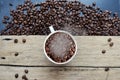 Steaming cup of coffee full of coffee beans in vintage wooden table with scattered beans around