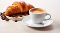 a steaming cup of coffee next to two golden croissants on a light surface