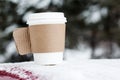 Steaming Cup of Hot Coffee or Tea standing on the Outdoor Table in Snowy Winter Morning. Cozy Festive paper cupwith a Warm Drink i
