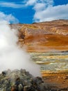 Steaming hot fumarole on geothermal field, yellow deposits of sulfates, red volcanic mountains, blue summer sky - Seltun Krysuvik Royalty Free Stock Photo