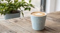 Steaming latte art in a teal cup on a wooden table Royalty Free Stock Photo