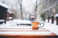 steaming mug of cocoa on snow-covered picnic table Royalty Free Stock Photo