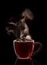 Steaming red cup filled with coffee beans Royalty Free Stock Photo