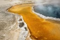 Steaming water and orange rim of hot spring in Yellowstone.