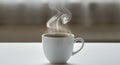 A steaming white ceramic cup filled with hot liquid is set on a smooth white surface. Royalty Free Stock Photo