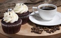 Steaming white coffee cup, homemade cupcake and coffee beans on brown wooden background, homemade cake