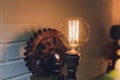 Steampunk architectural style design element of interior. Lamp bulbs fixed on iron industrial gear cogwheels sprocket