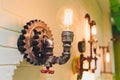 Steampunk architectural style design element of interior. Lamp bulbs fixed on iron industrial gear cogwheels sprocket