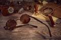 Steampunk still life - old vintage objects on a wooden background. Leather wrist watch, dark glasses, old tube lamps, magnifying g