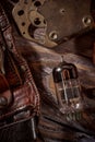 Steampunk still life - old vintage objects on a wooden background. Leather wrist watch, dark glasses, old tube lamps, magnifying g