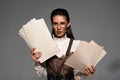 Steampunk woman in glasses holding documents and looking at camera on grey