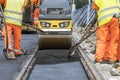 Steamroller workers construct asphalt road and railroad lines