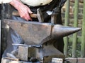 Steel anvil, on top of which lies a hot workpiece, the hand of the blacksmith processes a workpiece with the aid of a hammer