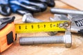 Steel bolt nuts and washers lie on wooden boards near an adjustable spanner and a tape measure Royalty Free Stock Photo