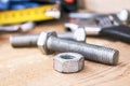 Steel bolt nuts and washers lie on wooden boards near an adjustable spanner and a tape measure Royalty Free Stock Photo