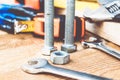 Steel bolt nuts and washers lie on wooden boards near an adjustable spanner and a tape measure Royalty Free Stock Photo