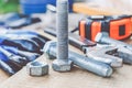 Steel bolt nuts and washers lie on wooden boards near an adjustable spanner and a tape measure Royalty Free Stock Photo