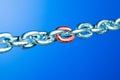 Steel chain with red link on blue background. Royalty Free Stock Photo