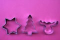 Steel Christmas tree, star, and deer shaped cookie cutters on red background with copy space. Royalty Free Stock Photo