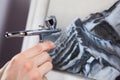 Steel chrome airbrush device in human hand, painting with aerograph, close-up view