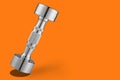 Steel chrome dumbbell, silver, on orange background, tilted as if falling, concept