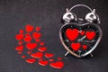 Steel clock alarm in the form of a heart with red hearts inside on a black glitter shiny background. Happy Valentine`s Day