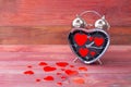 Steel clock alarm in the form of a heart, with a red hearts on a pink wooden background. Valentine`s Day