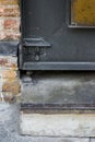 the steel door latch on black rustic steel door beside bare brick walls