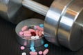 Steel dumbbell and colorful vitamins pills on the gym mat