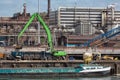 Steel factory in Dutch harbor IJmuiden with crane unloading barge