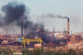 Steel factory with smog at sunset. Pipes with black smoke