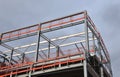 Steel frame building under construction with orange safety rail