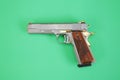 Steel gun or pistol inlaid with wood and gold isolated on a green background. weapon concept. protection and violence. copy space