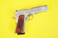 Steel gun or pistol inlaid with wood and gold isolated on a yellow background. weapon concept. protection and violence. copy space