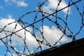 Steel, iron barbed wire on a background of blue sky with white clouds. Prison, camp. Royalty Free Stock Photo