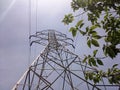 A steel-lattice power line tower with blue sky and summer leaves Royalty Free Stock Photo