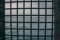 Steel mesh grid window in a castle looking out at the sea