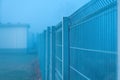 Steel metal fencing in foggy winter morning Royalty Free Stock Photo