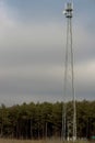 Steel mobile phone mast against the background of the forest .