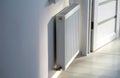 A steel panel heating radiator is placed under the windowsill on a white wall. Royalty Free Stock Photo