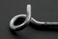 Steel pigtail screw hook on black background.