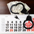 Steel police handcuffs, dollars money and April 15 on calendar o