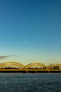 Steel railway bridge over Daugava during sunset and half moon