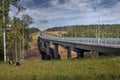 Steel road bridge on concrete supports, crosses forest stream.