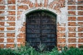 Steel rusty gates or door in red brick wall with grass at ruined ancient church Royalty Free Stock Photo