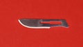 Steel scalpel blade on red background Royalty Free Stock Photo