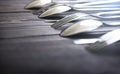 Steel spoons and forks in a row on a table. Royalty Free Stock Photo